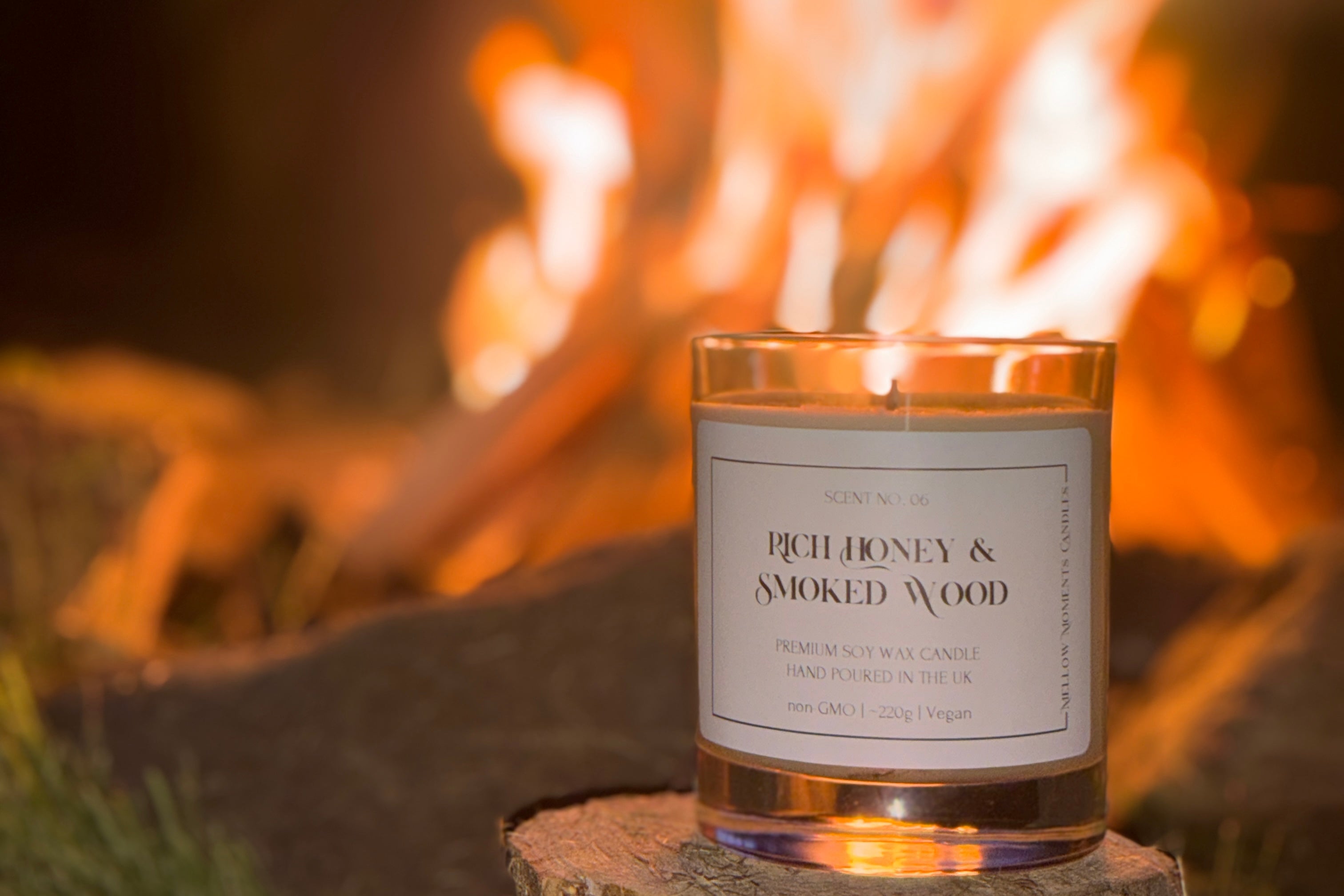 Candle scented 'Rich Honey & Smoked Wood' in front of an open fire on top of an oak block