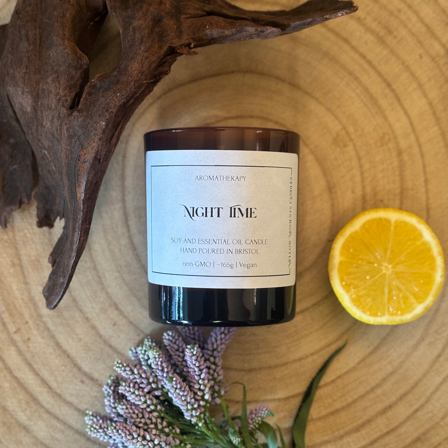 Candle labeled 'Night Time' on a wooden surface with a lemon, wood, and lavender.